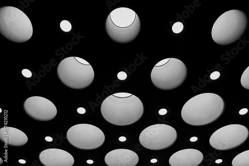 Abstract ceiling pattern of circular lights, modern architecture design, minimalistic geometric shapes, creative symmetry, futuristic interior atmosphere, black and white contrast.