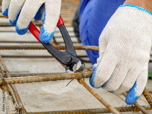 Fotografi Closeup shot of bar bender hands fixing steel reinforcement bars using pincers