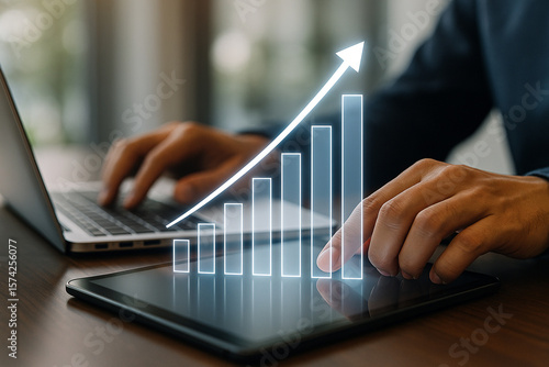 Business growth strategy using laptop and tablet with financial chart and arrow going up concept
