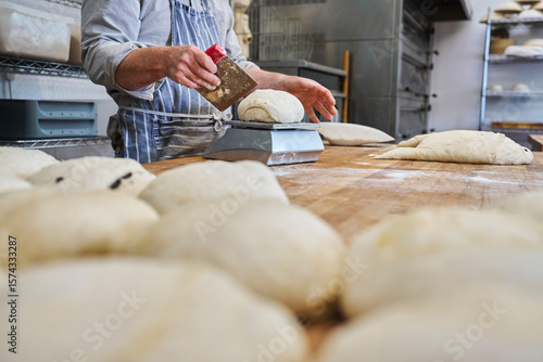 Foto Close up of baker cutting and weighing batch of dough to make individual loaves