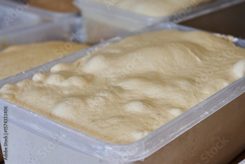Фотография Close up of sourdough fermenting in containers in bakery