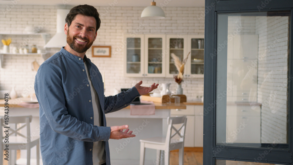 Fototapeta premium Cheerful glad Caucasian man dad smiling gesturing with hands inviting to new house dwelling happy adult male father come inside for visit gesture housewarming welcoming sign mortgage rent loan at home