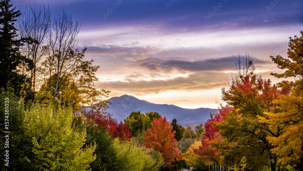 Obraz premium Vibrant autumn trees frame a majestic mountain under a colorful twilight sky