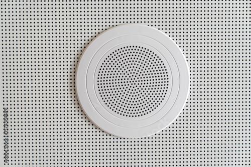 Close up view of a speaker on a white background, on a wall or ceiling.