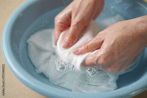 Hands Washing White Fabric in Blue Basin water