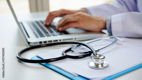 Doctor typing on laptop with stethoscope and medical chart image