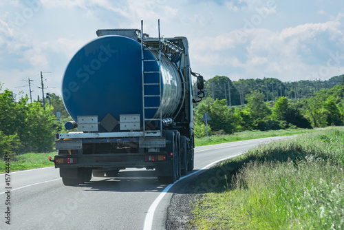 A fuel truck with a blue tanker drives along a country asphalt road