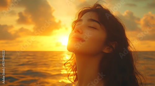 Peaceful young woman gazing at a golden sunrise.