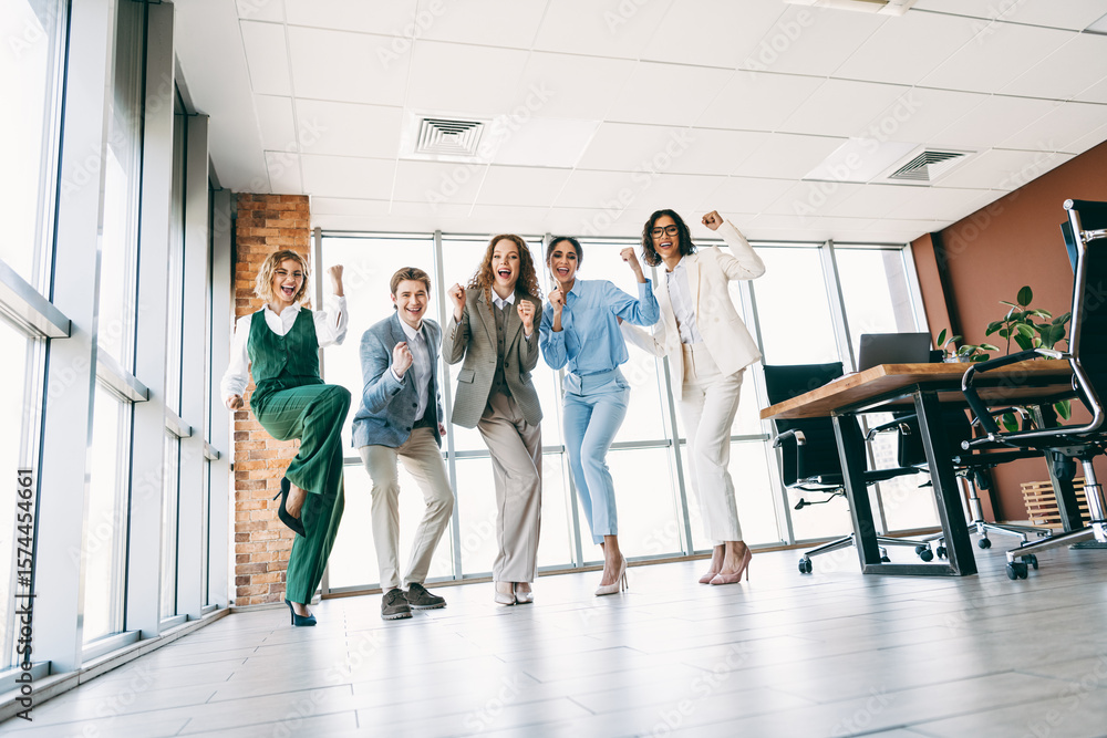 Fototapeta premium Joyful group of professionals celebrating teamwork success in a modern office space with bright and welcoming ambiance