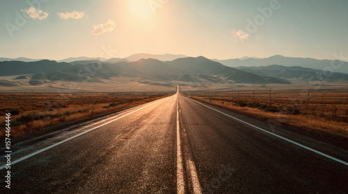 The open road leads towards majestic mountains under a warm sunset.