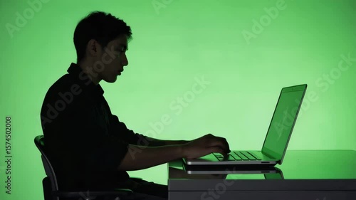 Side-view silhouette of a person working on a laptop, fingers tapping keys, chroma green background for overlay use, tech workspace pose, minimalist modern posture