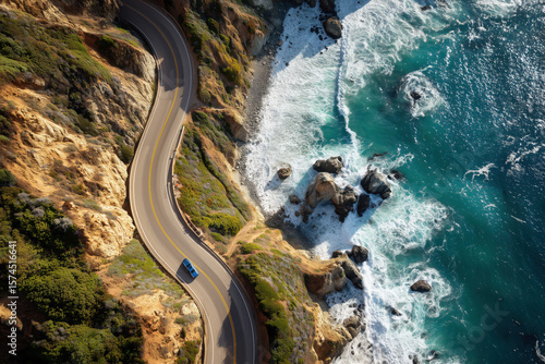 Aerial view of a car driving along coastal road surrounded by cliffs and ocean