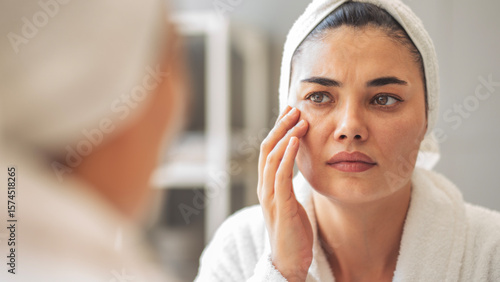 Foto Woman looks in the mirror noticing the first wrinkles