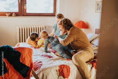 Fotografie A joyful moment of a family playing with their children on a bed in a warm, inviting environment, emphasizing family bonds and care