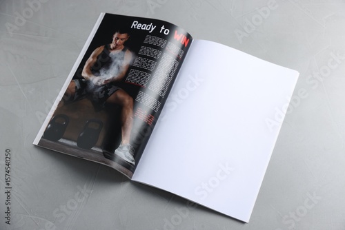 Open magazine on light grey table. Mockup for design