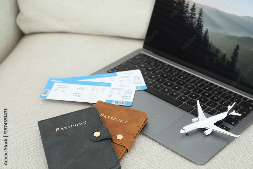 Obraz premium Passports, flight tickets, plane model and laptop on sofa, closeup