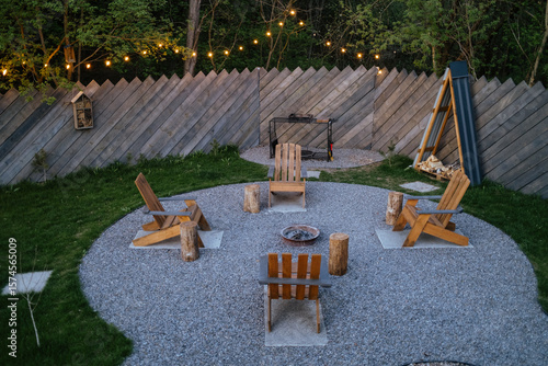 Cozy backyard fire pit area with wooden chairs, string lights, evening gathering
