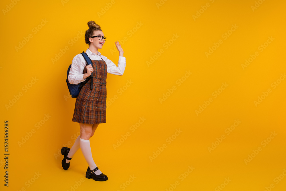 Fototapeta premium Charming young student posing on vibrant yellow background wearing stylish uniform, showcasing youthful energy and cheerfulness