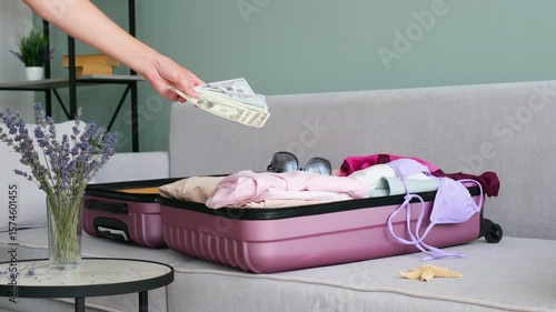 A woman puts money in a suitcase for a trip