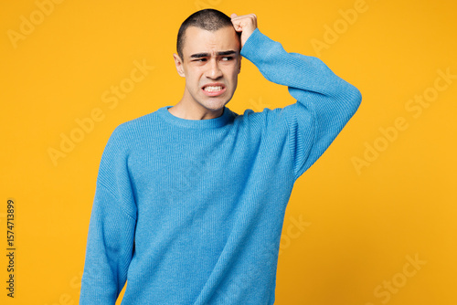 Young sad embarrassed mistaken middle eastern man he wearing blue sweatshirt casual clothes looking aside on area mock up isolated on plain yellow orange background studio portrait. Lifestyle concept.