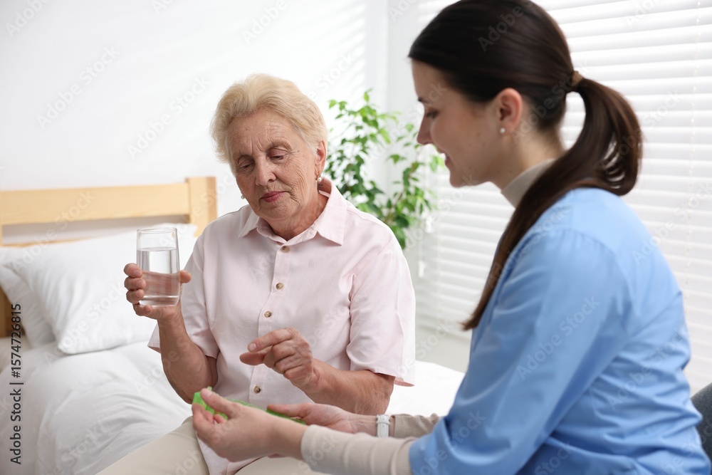 Obraz premium Nurse giving pills to senior woman indoors. Home health care service