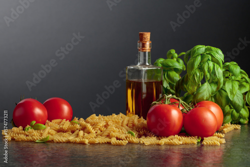 Fusilli pasta with olive oil, tomatoes and basil on a black background. © Igor Normann