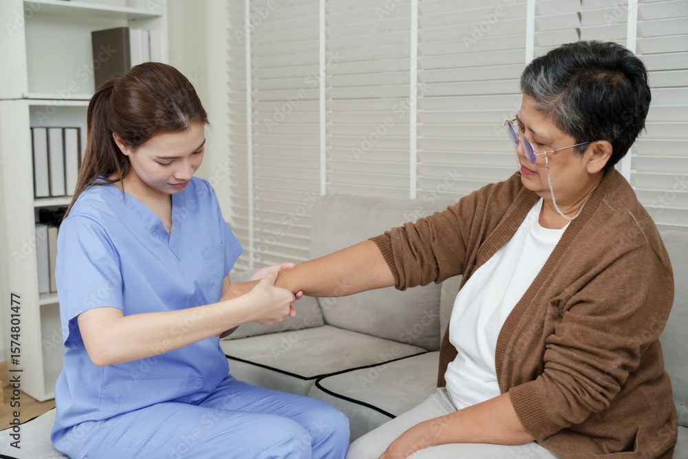 Obraz premium Senior asian woman undergoing physical arm therapy with female therapist stretching arm slowly forward on sofa during rehabilitation focusing on muscle mobility and recovery