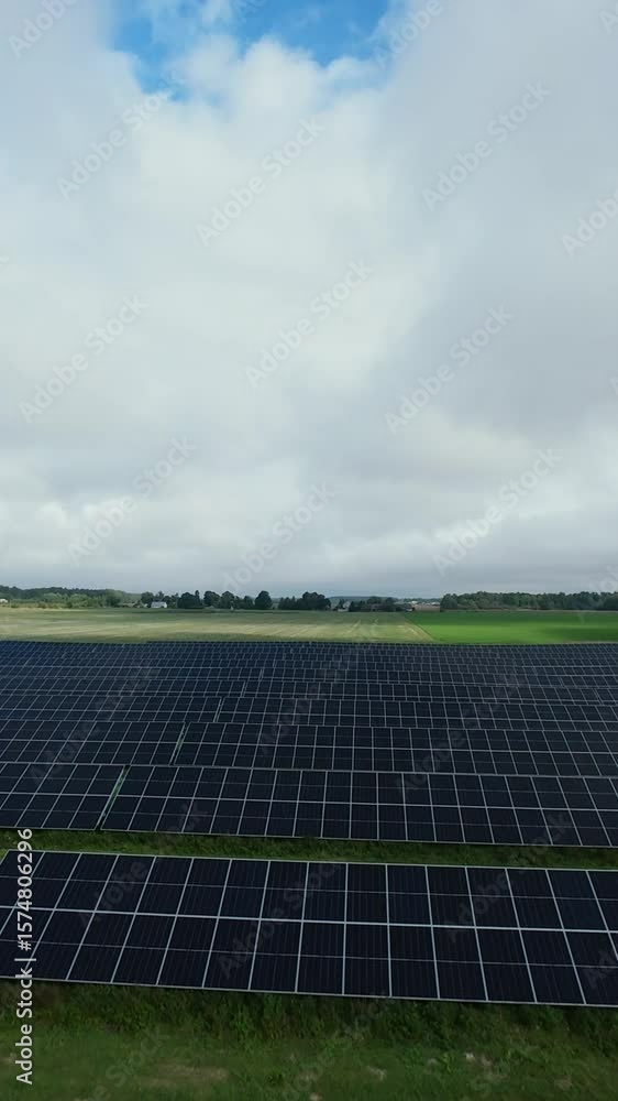 Vertical screen Wide solar panel installation with black panels under blue sky and white clouds Expansive solar field with black photovoltaic panels under bright cloudy sky renewable energy landscape Vertical screen Wide solar panel installation with black panels under blue sky and white clouds Expansive solar field with black photovoltaic panels under bright cloudy sky renewable energy landscape