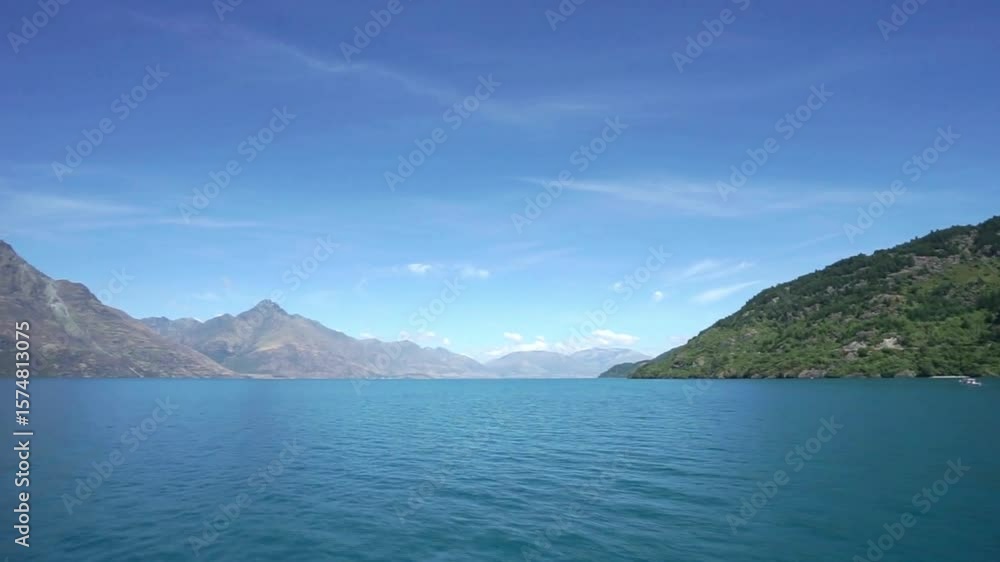 A scenic view of a lake surrounded by mountains under a blue sky A scenic view of a lake surrounded by mountains under a blue sky