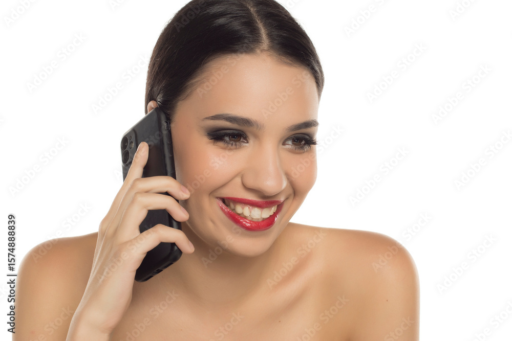 Smiling glamorous woman with red lipstick talking on smartphone, studio shot on white background Smiling glamorous woman with red lipstick talking on smartphone, studio shot on white background