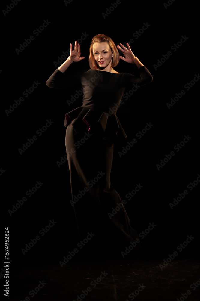 Fototapeta premium Woman in a black dress posing on a black background