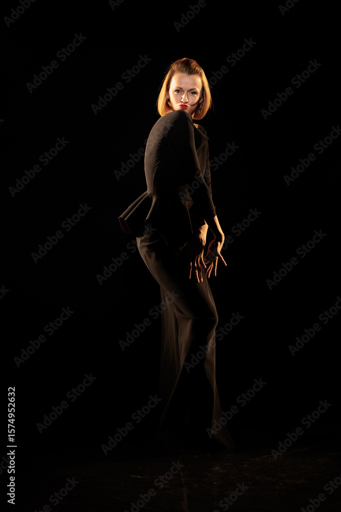 Fototapeta premium Woman in a black dress posing on a black background