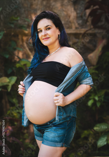 pregnant woman with exposed belly, colored hair, outdoors in jeans and black top.