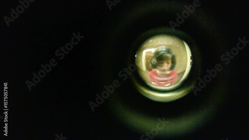 Looking through peephole at woman in hotel hallway