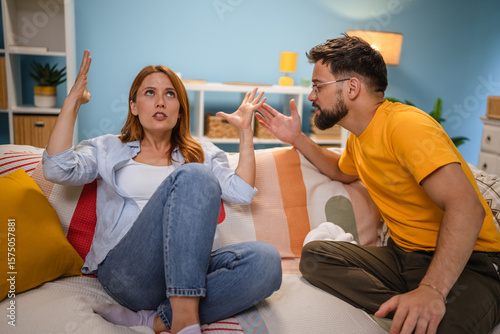 Fotografie Caucasian stressed couple sitting on couch, arguing at home.