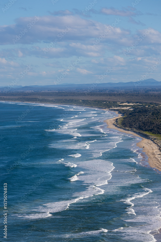 Obraz premium Aerial view of beach coastline with few waves.
