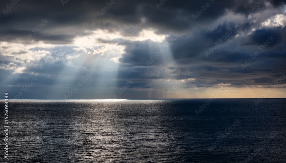 Obraz premium rays of sunlight break through dark clouds over a tranquil ocean at midday