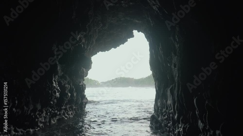 Wide shot of a sea cave opens to the ocean and distant land.