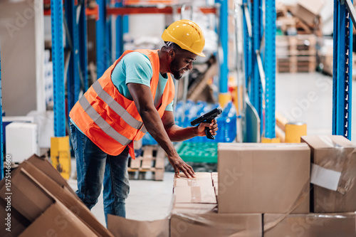 Fotografie Warehouse worker scanning packages with barcode scanner in distribution center