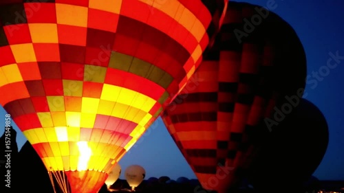 Hot air balloons glow against the dark blue night sky