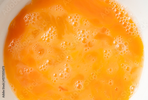 Fotografie Close-up of beaten egg yolks with bubbles. Top view shot