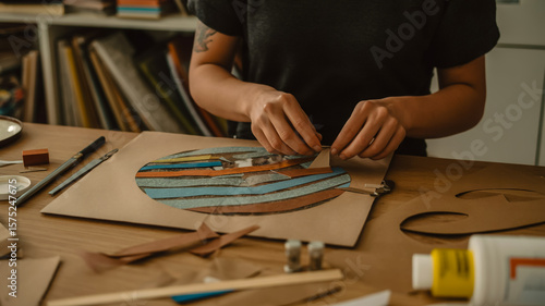 Closeup of an artists hands creating a paper collage on a wooden table