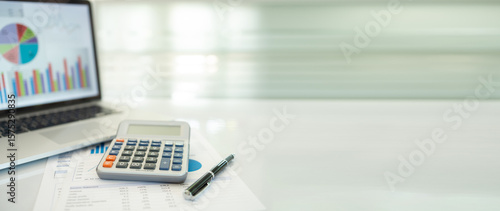 calculator, business report and financial portfolio show on screen laptop computer. with review of year end reports. accounting business concept.