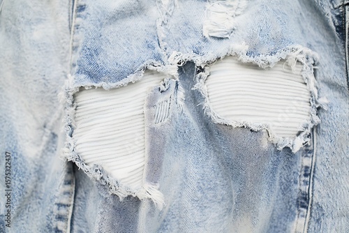 Closeup of Ripped Light Blue Denim Jacket with White Striped Patch Showing Through