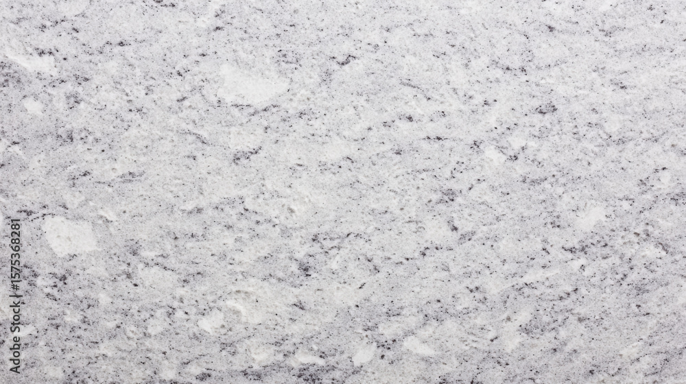 Fototapeta premium The textured surface of white granite rock shows an abstract and natural pattern with visible color variations and specks, creating a background ideal for designs.