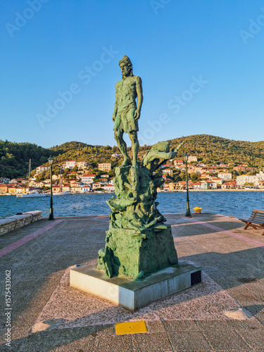 Odysseus Statue in Ithaca island,  with colorful Ionian houses in the background and the bay of  Vathy, Ithaca island, the island home of the hero Odysseus, Greece 