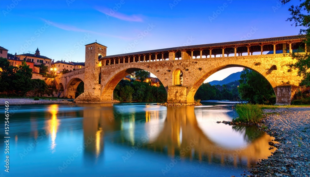 Fototapeta premium Ancient bridge over calm river at dusk