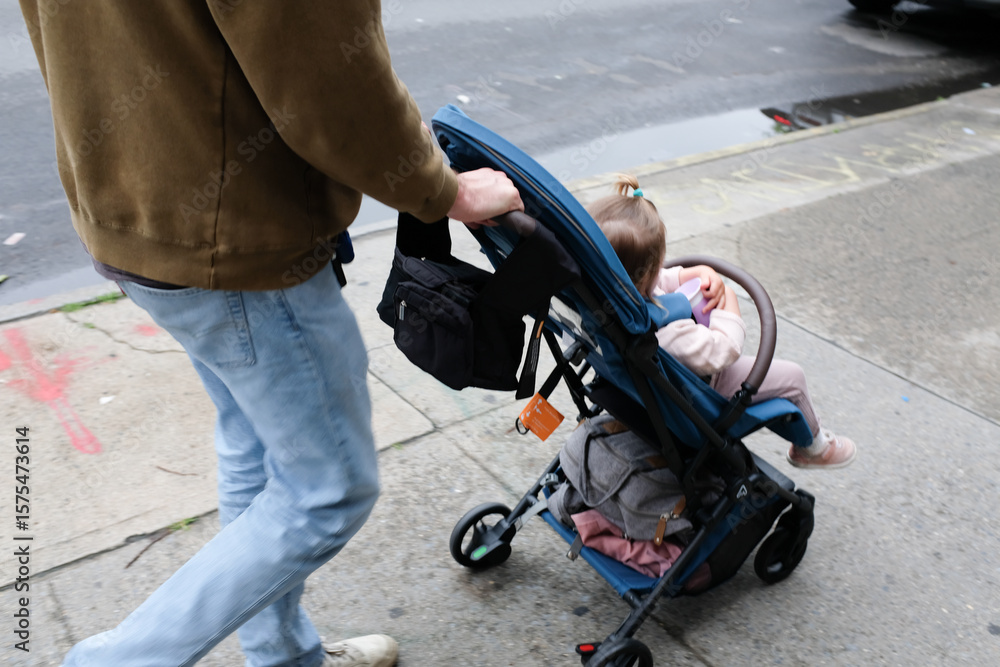 Obraz premium Millennial Dad Pushing Toddler Daughter on Brooklyn Sidewalk