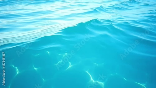 A clear, tranquil blue water surface with gentle ripples and beautiful sunlight creating caustic light patterns.