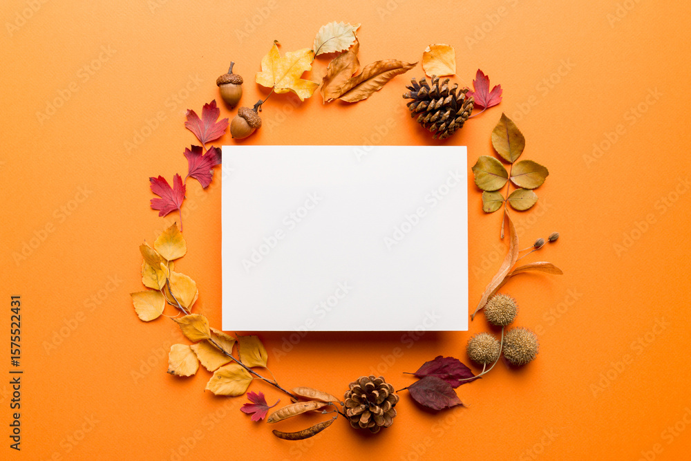 Fototapeta premium Autumn composition with paper blank and dried leaves on table. Flat lay, top view, copy space